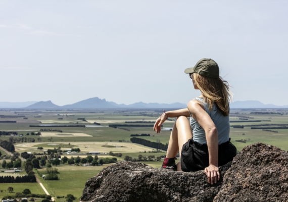 Female sitting on a rock on Mount Rouse overlooking the Volcanic plains